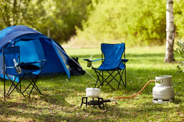旅行のコンセプト キャンプ場の観光ガスバーナー 青いテントと2つの折りたたみ椅子のキャンプ場の近く ストック画像