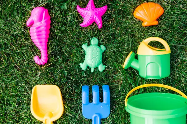 童年和夏季的概念 在绿色草坪或草地上封闭沙生玩具套件 免版税图库图片