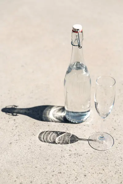 オブジェクトと飲み物のコンセプト 日当たりの良い床に水とガラスのボトル ストックフォト