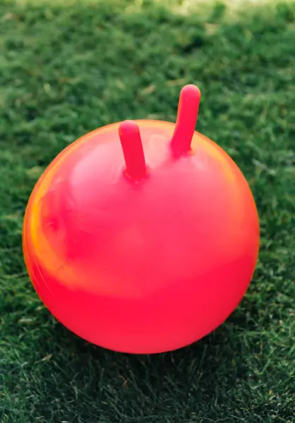 子供時代 レジャー おもちゃのコンセプト 芝生の上で赤いバウンスボールやホッパーのクローズアップ ロイヤリティフリーのストック写真