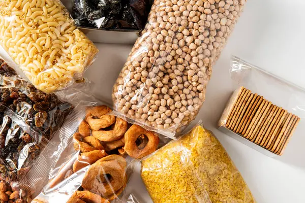 食物贮存和健康饮食概念 关闭袋与干果 意大利面和坚果的白色背景 顶部视图 免版税图库图片