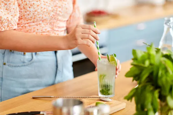 飲み物と人のコンセプト 家庭用キッチンでライムモヒートカクテルを作る紙の藁で女性のクローズアップ — ストック写真