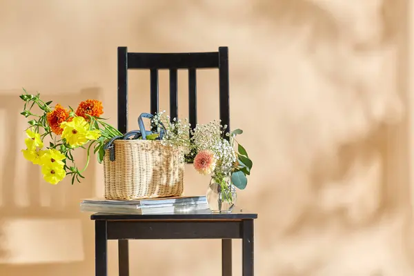 家居装饰和设计理念 在米色背景之上的老式椅子上 把篮子和杂志中的花朵关起来 图库图片