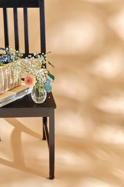 家居装饰和设计理念 在米色背景之上的老式椅子上 把篮子和杂志中的花朵关起来 图库照片