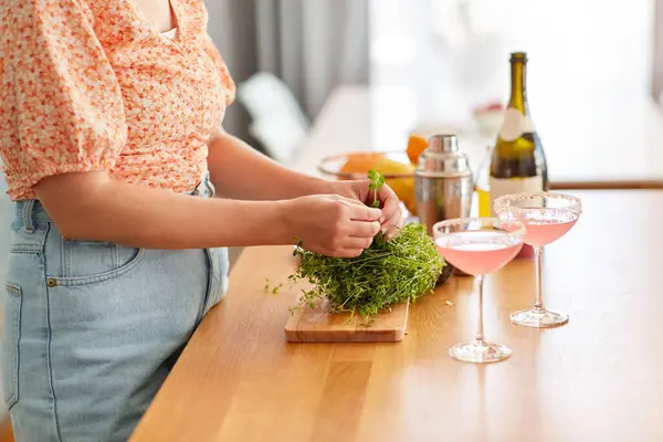 酒水和人的概念 在家里厨房用百里香和酒杯做鸡尾酒的女人的近照 免版税图库图片