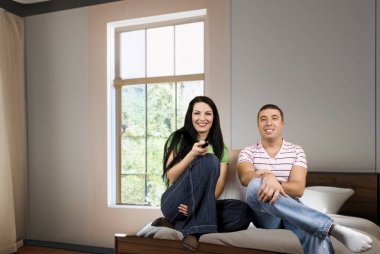 Kanepede televizyon seyreden genç ve mutlu bir çift. Kanal değiştirip eğleniyorlar.