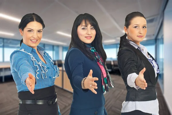 Female group smiling indoors at an office, radiating happiness.
