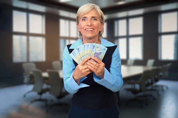 一位老年妇女将罗马尼亚货币放在会议室里 象征着金融讨论和商业观点的多样化 图库图片