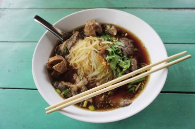 Yeşil masa arkasında haşlanmış domuz çorbası ile erişte.