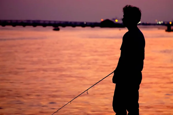 日没の空と海の背景を持つポートでの人間釣りのシルエット — ストック写真