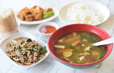 Kuzeydoğu Tayland mutfağı, kızarmış domuz ciğeri baharatlı salata, tatlı soslu kızarmış tavuk tendonları, baharatlı Tayland çorbası, bitkilerle pilav.