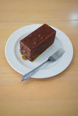 Çikolata kaplı, beyaz tabakta kremalı pasta, tatlı menüsü.