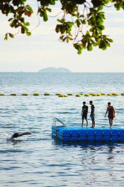 PATTAYA, THAILAND: 2 Temmuz 2024 'te Pattaya, Chonburi, Tayland' da bir saldan denize atlayan bir grup genç