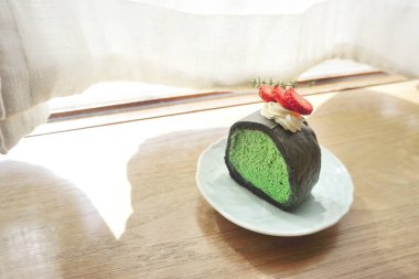 Ahşap masada kibrit yeşil çay köpüklü kek.