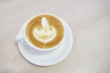 Sütlü kahve, latte sanatı, ahşap masada sıcak kahve.