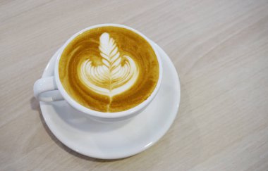 Ahşap sehpada Latte sanat kahvesi, yüksek açı manzaralı.