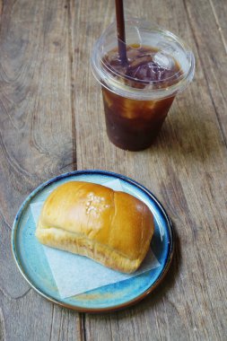 Amerikan kahvesi ve ahşap masada ekmek.