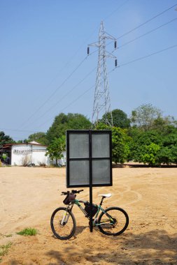 CHONBURI, THAILAND - 21 MAR: 21 Mart 2025 tarihinde Sriracha, Chonburi, Tayland 'da yüksek voltajlı elektrik direği arka planı ile dağ bisikleti parkı tabelasında
