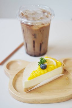 Mango meyveli kek yakın çekim meyve ve buzlu kahve arka plan ile dekore 