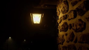 Gece vakti karanlık gökyüzünün üzerindeki eski ortaçağ taş evinin dışında fener var.