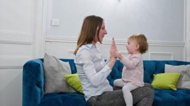 Genç anne kucağında bebekle kanepede oturuyor.