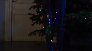 Smiling face of happy boy with Christmas lights  near New Year tree