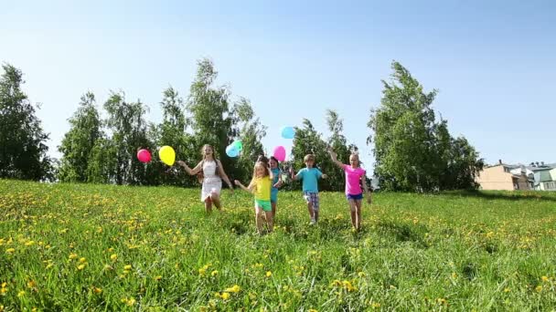 在阳光明媚的日子 一群男孩和女孩拿着气球在春天的蒲公英地里奔跑 — 图库视频影像