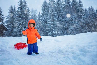 Cute boy run on uphill with the sled to go downhill, over the mountain peaks on winter vacation during snowfall
