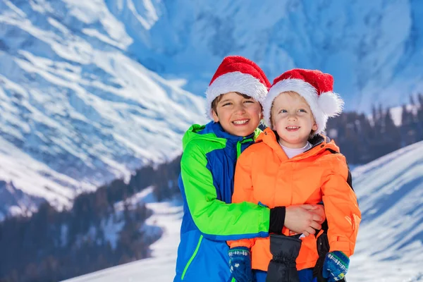 Two Happy Brothers Santa Claus Hats Stand Hugging Winter Snow — Fotografia de Stock