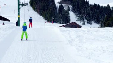 Çocuk güneşli bir günde Alp Tatil Köyü 'nde kayak asansörüyle yukarı çıkıyor.