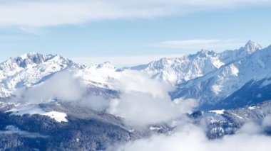 Fransız Alplerinde dağ, Mont Blanc yığını altında kalın bulutlar, yukarıda parlak güneş ve kar fırtınası üstüne çalılar.