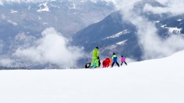 Many skiers on alpine ski resort go down the slope view from above on sunny day