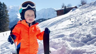 Little boy in ski school three years old child stand over mountains on background