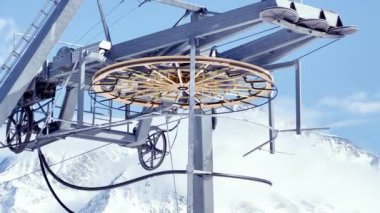 Close up of beautiful mechanic big ring with cables from the ski lift over the mountain on background