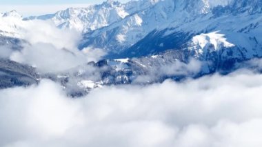 Mountain in French Alps Mont Blanc massif with thick clouds below, bright sun above and snow covered bushes after snowstorm