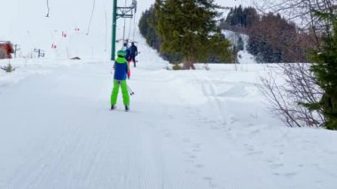 Boy go up holding t-bar ski lift on alpine resort sport vacation on sunny day