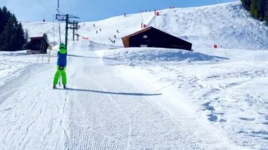 Boy go up holding t-bar ski lift on alpine resort sport vacation on sunny day