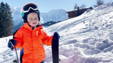 Little boy in ski school three years old child stand over mountains on background