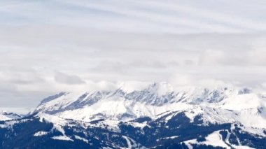 Mountain in French Alps Mont Blanc massif with thick clouds below, bright sun above and snow covered bushes after snowstorm