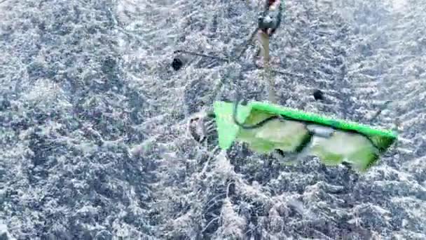 滑雪车的绿色椅子在被雪覆盖的森林里沿着绳索移动 — 图库视频影像