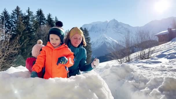 ファミリー 山の休暇で雪の要塞で一緒に遊ぶ女の子と男の子の母親 — ストック動画