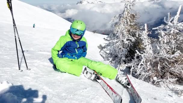 Маленький Хлопчик Альпійськими Лижами Сидить Снігу Спостерігаючи Горою Над Вершинами — стокове відео