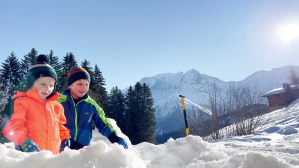 冬休みに二人の男の子兄弟は山の上の雪の要塞で遊ぶ — ストック動画
