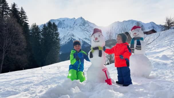Two Little Boys Brothers Snowmen Snow Mountain Background — Stockvideo