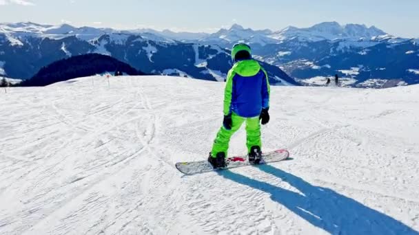 Snowboard Hareket Halindeki Çocuk Arka Plandaki Alp Dağlarının Zirvelerinde Kayıyor — Stok video