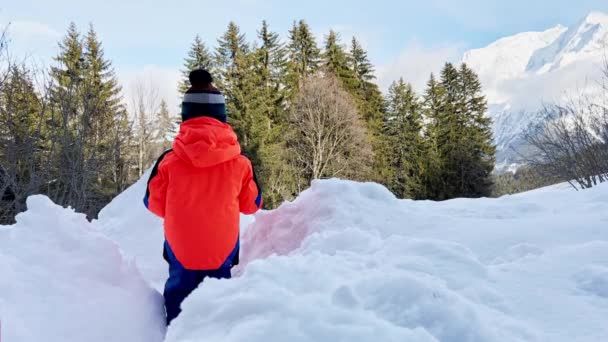 小さな男の子でオレンジコート遊びで雪の外で晴れた冬の日 — ストック動画