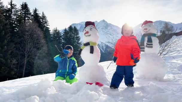 二人の少年雪の山の外に雪の男の兄弟 — ストック動画