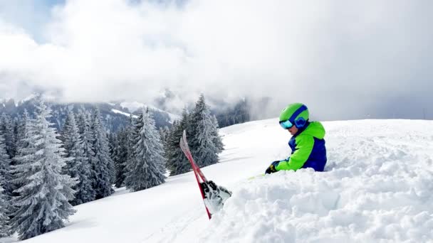 Ragazzino Con Sci Alpino Seduto Sulla Neve Che Osserva Montagna — Video Stock