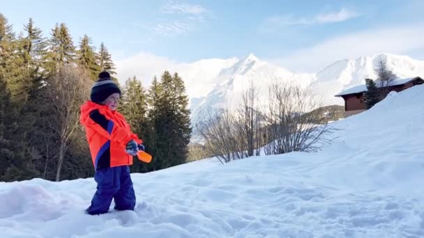 Маленький Хлопчик Помаранчевому Пальто Грає Лопатою Снігом Вулиці Сонячний Зимовий — стокове відео
