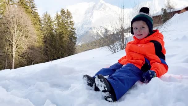 Glücklicher Kleiner Junge Winteroutfit Spielt Draußen Schnee Mit Bergen Hintergrund — Stockvideo